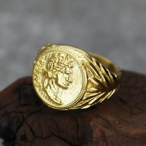 Macro detail of golden Caesar emblem seal ring with vintage Roman laurel leaf carving