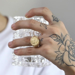 Macro detail of men's vintage gold lion signet ring worn by model with textured glass