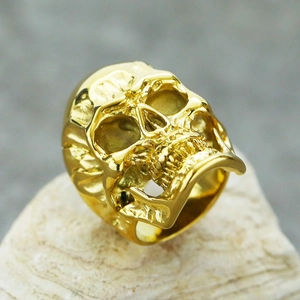 Macro close-up of golden punk skull ring with detailed carving on a white rock