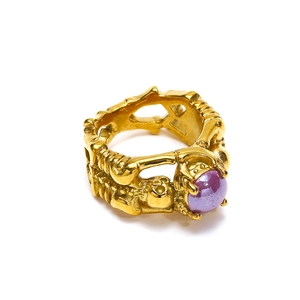 Macro shot of punk skull relief engraving and purple cabochon on a gold ring band
