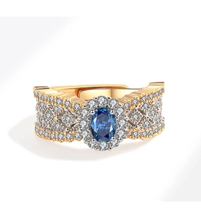 Macro view of wide gold band ring featuring a blue oval gemstone and pavé diamonds