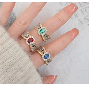 Macro side view of three vintage-style rings with red, green, and blue oval gemstones