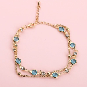 Bracelet double rang en cuivre doré avec pierres bleues et strass blancs sur fond rose