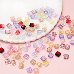 Mix of gradient floral glass beads for DIY jewelry making on white ceramic plate