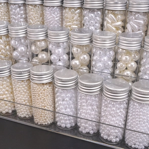 Multiple sizes of white and cream ABS pearls stored in clear glass jars on a display stand