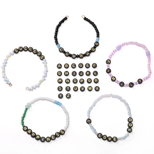 Close-up of 4x7mm black acrylic alphabet beads with gold letters for DIY jewelry making