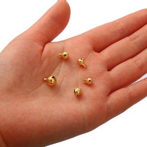 Mini pendentifs cloches plaqués or 18K pour bijoux DIY présentés dans la main