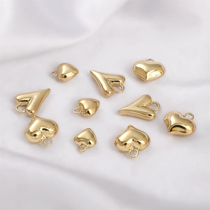 Makroaufnahme von 14K Gold gefüllten Herzanhängern auf Seide für DIY Schmuckherstellung