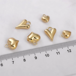 Makroaufnahme von 14K vergoldeten Herzanhängern mit Lineal für präzise Größenanzeige