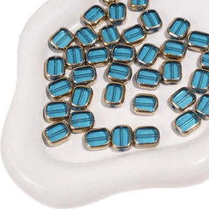 Close-up of 10x12mm blue glass beads with gold metal frames for DIY jewelry making