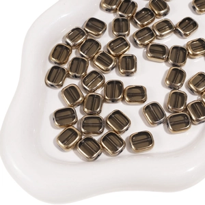 Macro view of oval glass beads with gold metallic edges and smoky gray centers for jewelry