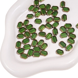 Macro detail of 6x9mm green faceted glass beads with gold-rimmed edges for DIY jewelry