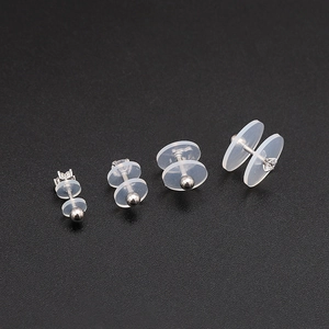 Detail shot of clear silicone earring backings in four sizes on a dark textured background