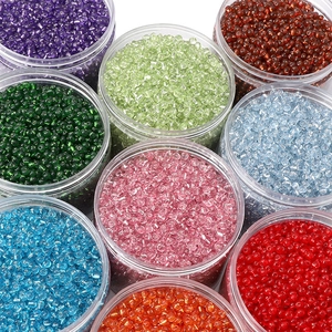 Overhead view of colorful 4mm glass seed beads organized in clear round jars for DIY jewelry