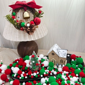 Miniature snowy wooden house with colorful Christmas pompoms and festive wreath decor