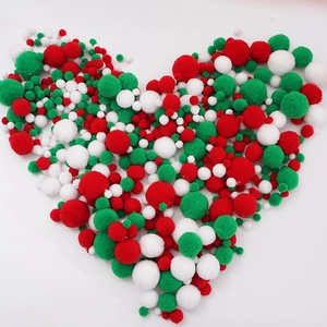 Red, green, and white Christmas pom-poms arranged in a heart shape for DIY crafts