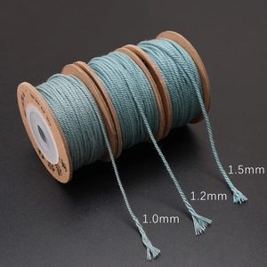 Dusty blue braided polyester cords in 1.0mm to 1.5mm sizes on wooden spools for DIY crafts