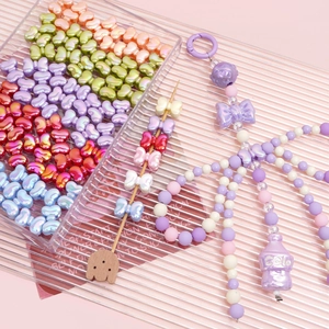 Colorful acrylic iridescent bow beads for DIY jewelry making displayed on a tray