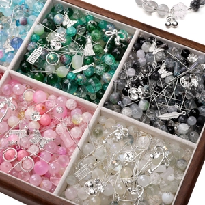 Macro view of assorted glass beads and silver alloy charms in a wooden organizer box