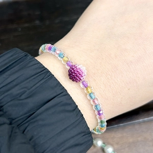 Detailed shot of a colorful glass seed bead bracelet with a purple woven centerpiece bead