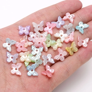 Macro detail of 10x11mm pearlescent butterfly beads for DIY jewelry making in a palm