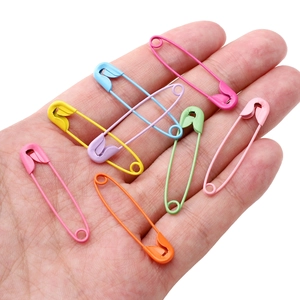 Colorful painted iron safety pins held in hand for size reference with vibrant multi-colors
