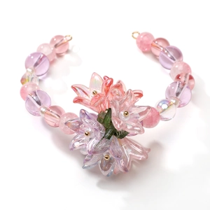 Detail view of handmade pink and purple acrylic lily flower charms and beaded bracelet