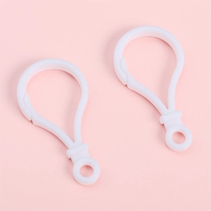 Détail de deux fermoirs mousquetons en acrylique blanc pour porte-clés DIY sur rose