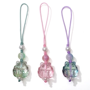 Detailed view of three cat-shaped glass pendants in green, purple and iridescent finishes