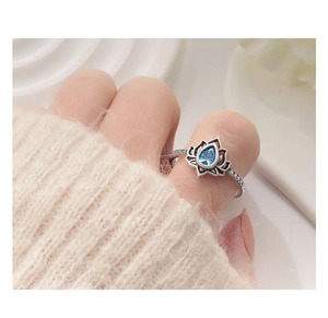 Dettaglio anello loto vintage con zircone blu a goccia su vassoio bianco