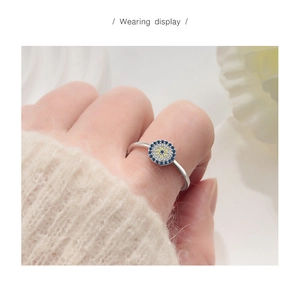 Macro detail of silver evil eye ring with blue and yellow stones worn on finger