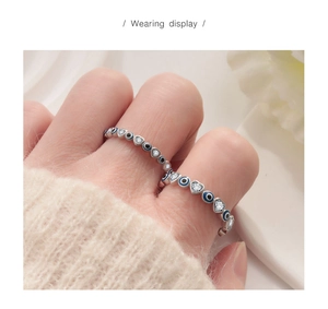 Close-up of S925 silver evil eye and heart zircon open rings stacked on fingers