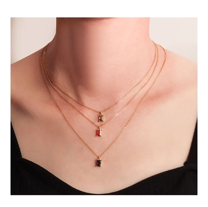 Close-up of triple-layered gold-plated necklaces with emerald, ruby and sapphire pendants