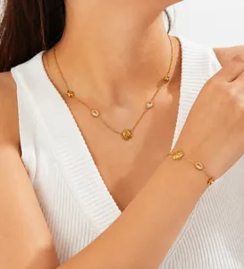 Close-up of gold stainless steel necklace set with star and sun pendants on a model