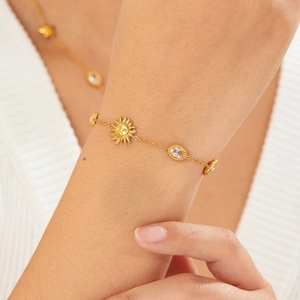 Gold stainless steel chain bracelet featuring sun face pendant and oval crystal charms