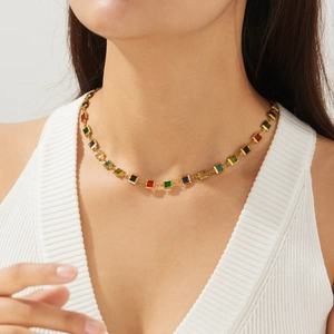 Detailopname van een gouden ketting met veelkleurige vierkante kristallen op een model