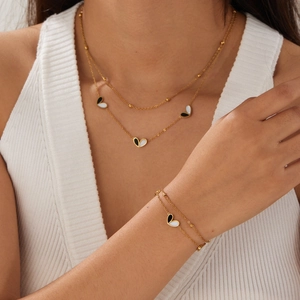 Gold double-layer necklace and bracelet set with black and white heart pendants