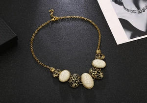 Detail of bohemian gold chain necklace with oval marble texture and floral patterned charms