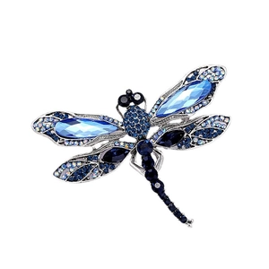 Élégante broche libellule argentée avec cristaux bleus et strass sur fond blanc épuré
