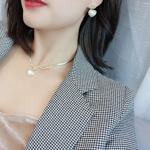 Elegante gouden hartparel ketting en oorbellen set gedragen door een fashion model