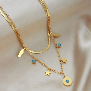 Collier double couche doré avec pendentifs plume et turquoise sur fond de satin soyeux
