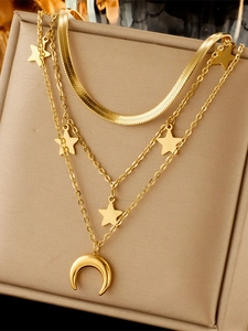 Close-up of gold layered necklace with star and moon charms on a professional stand