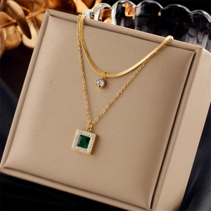 Layered gold titanium necklace with emerald pendant and white crystal stone on display box