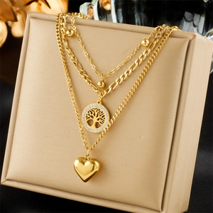 Three-layer gold titanium necklace with tree of life and heart pendants on jewelry box