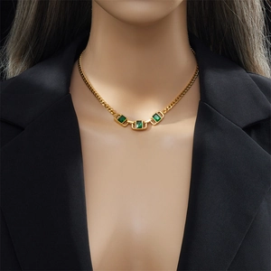 Collana vintage dorata con tre pietre quadrate verde smeraldo su un blazer nero
