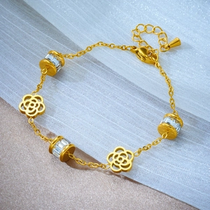 Elegant gold titanium bracelet featuring white camellia charms and sparkling rhinestones