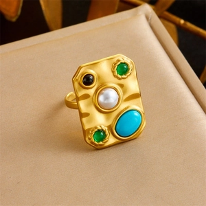 Detail of vintage gold plated ring with irregular texture, pearl and colorful stones