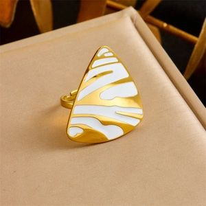 Macro shot of gold-plated ring with triangular white enamel pattern and open band