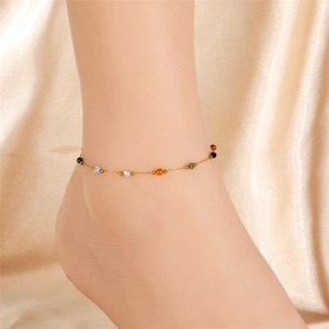 Detail of colorful beaded stainless steel anklet on a soft champagne satin background