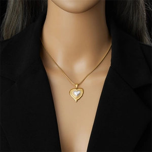 Elegante goldene Herzkette mit Perleneinlage getragen auf schwarzer Kleidung